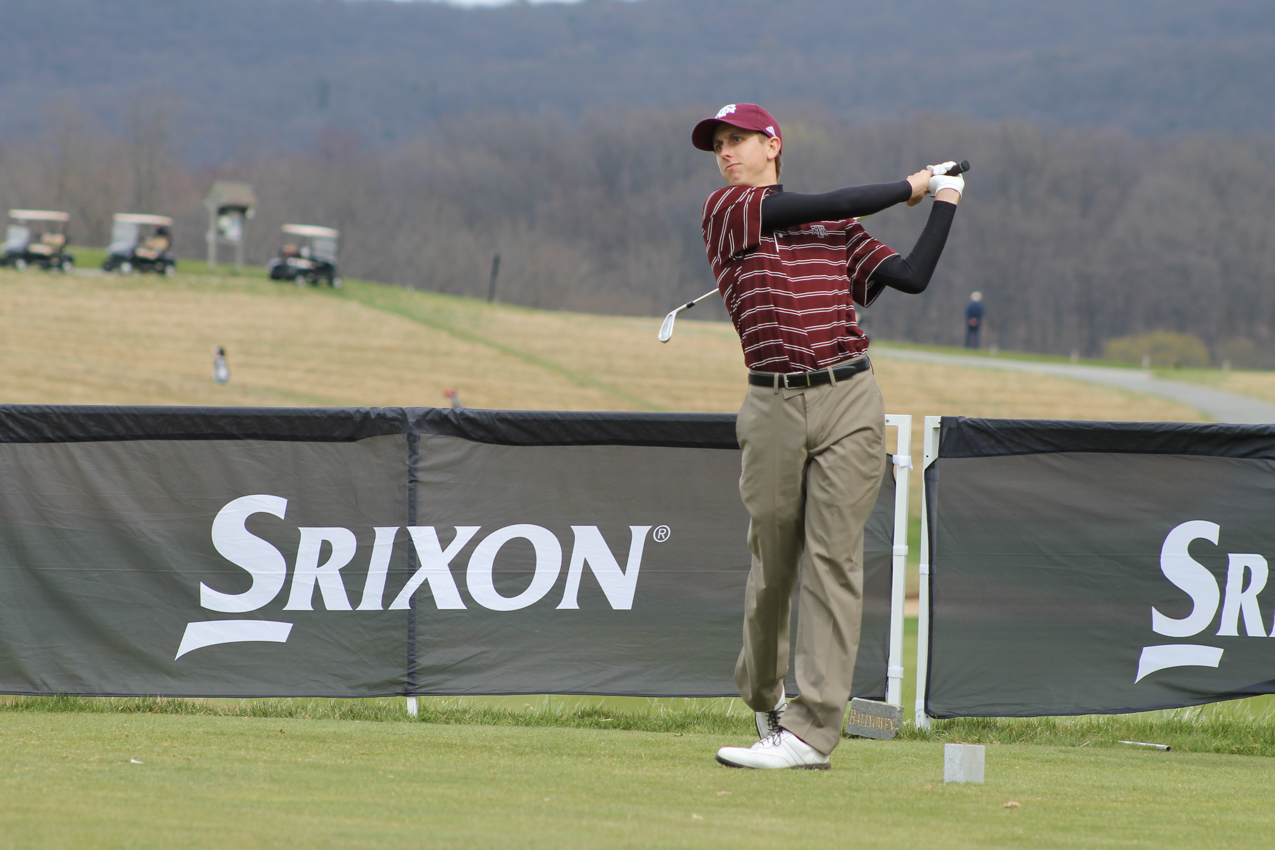 Golfer In maroon teeing off at the hole